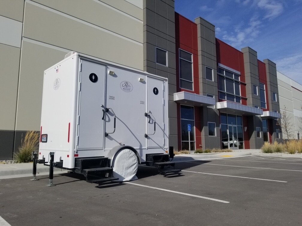 Luxury portable restroom trailer parked outside a modern building in Colorado.