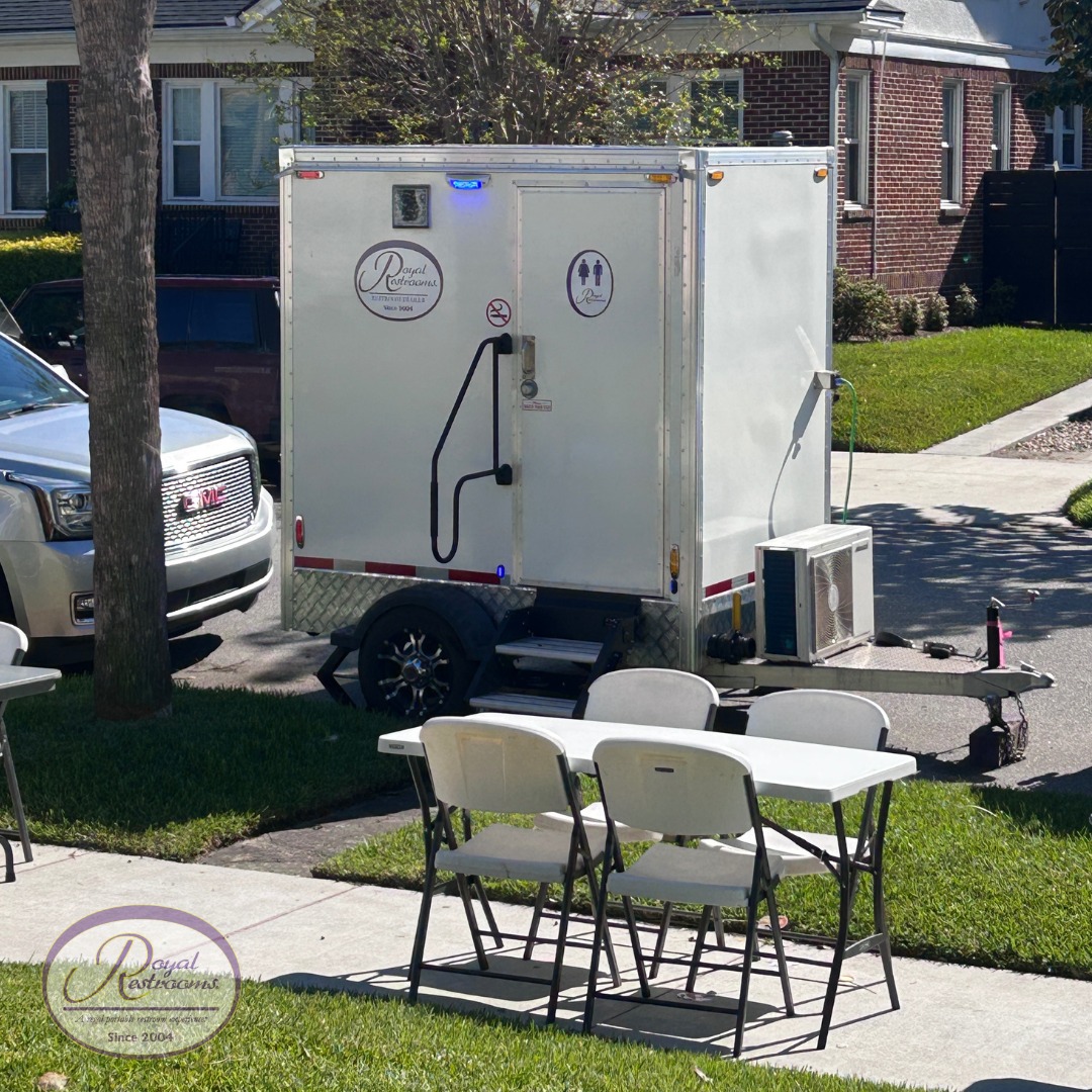 Luxury portable restroom with three urinals, framed mirrors, and floral decor inside.
